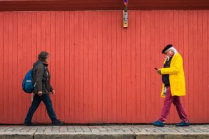 Punaiseksi maalattu puinen rakennuksen julkaisivu jonka edessä kaksi ihmistä kävelee vastakkain