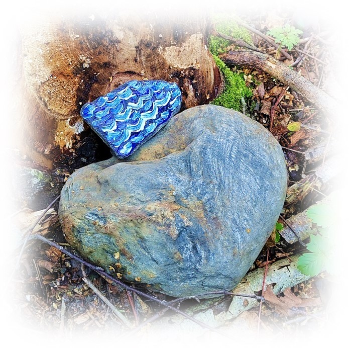 Maalattu pieni sininen kivi isomman luonnonkiven vieressä